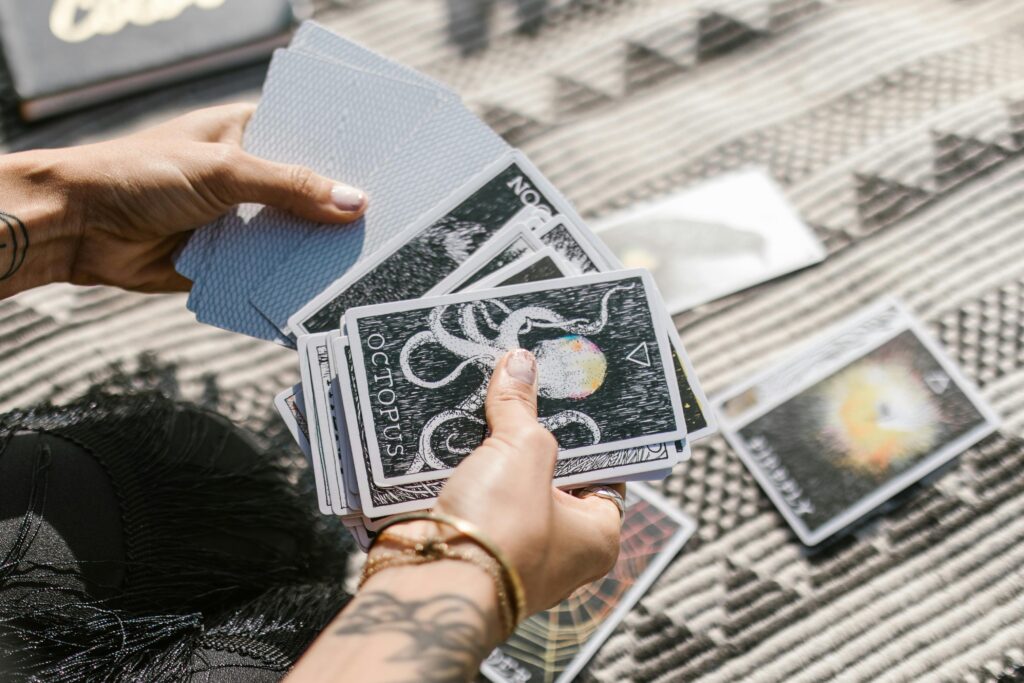 pexels-photo-6806667-6806667 Hands holding tarot cards during a reading session on a patterned mat.